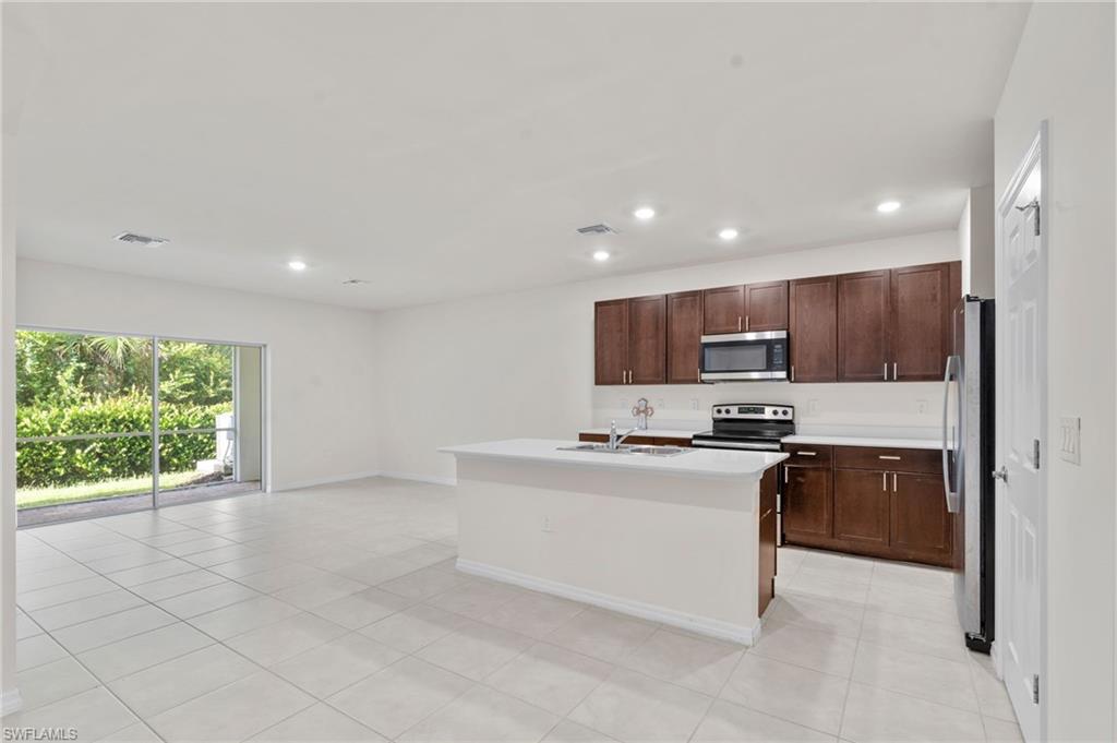 Kitchen with appliances with stainless steel finishes, recessed lighting, light tile patterned floors, an island with sink, and open floor plan
