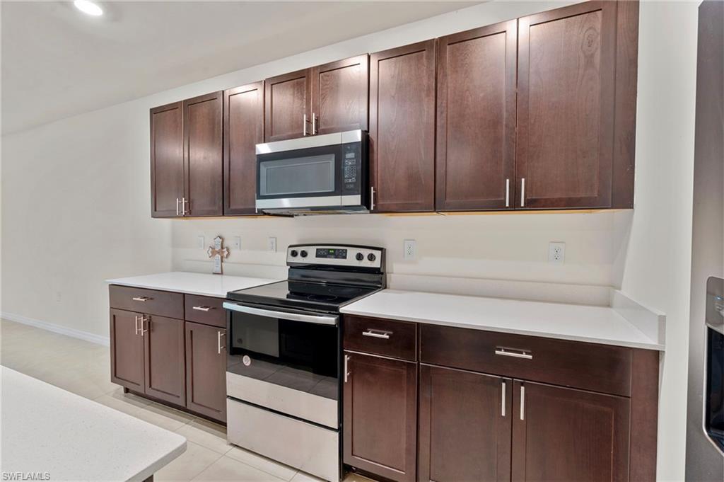 Kitchen featuring stainless steel appliances, dark brown cabinets, and light tile patterned floors
