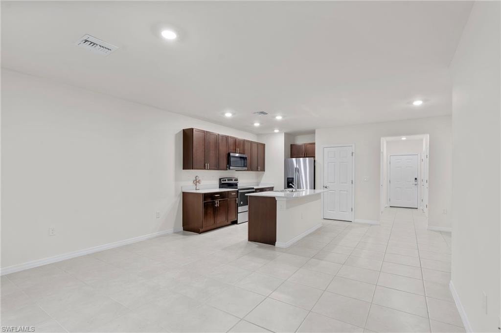 Kitchen with an island with sink, stainless steel appliances, dark brown cabinets, recessed lighting, and a kitchen breakfast bar