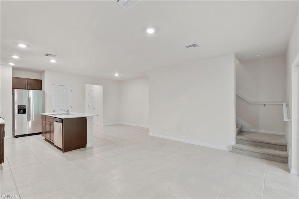 Kitchen featuring stainless steel appliances, an island with sink, dark brown cabinetry, recessed lighting, and light tile patterned flooring