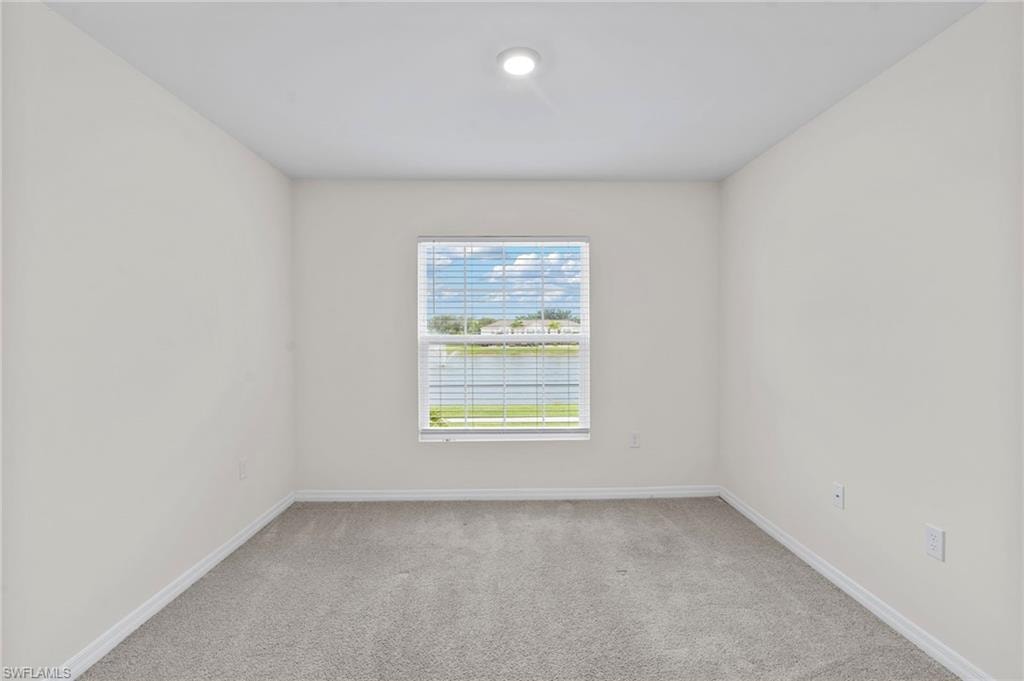 Unfurnished room with light colored carpet and a water view