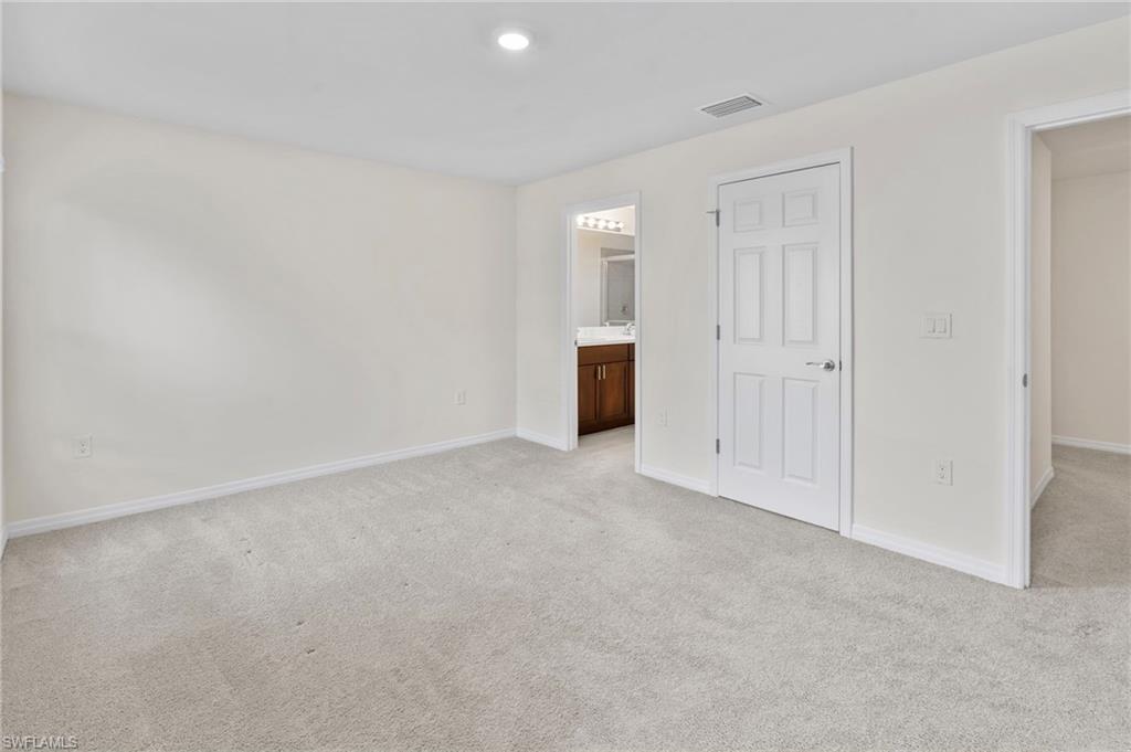 Unfurnished bedroom featuring light colored carpet and ensuite bath