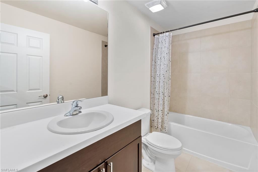 Bathroom with shower / tub combo, vanity, and light tile patterned flooring