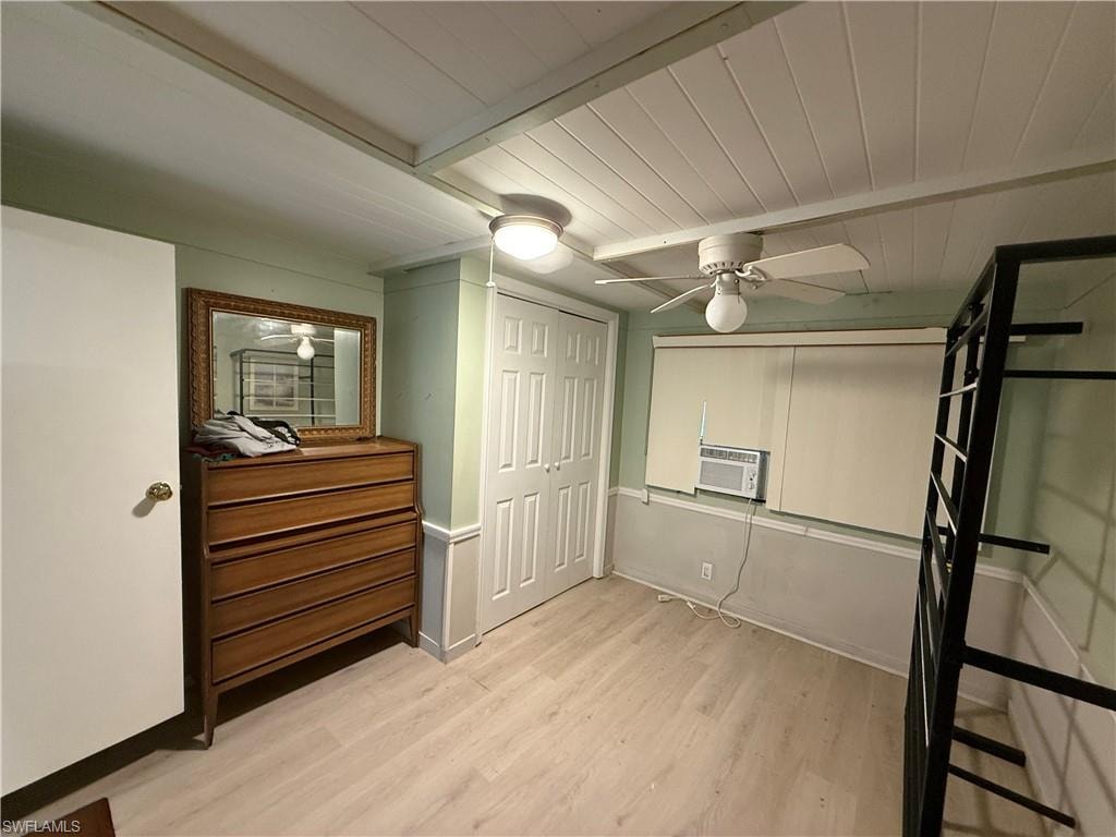 Unfurnished bedroom featuring a closet, light wood-type flooring, ceiling fan, and a wood ceiling with exposed beams