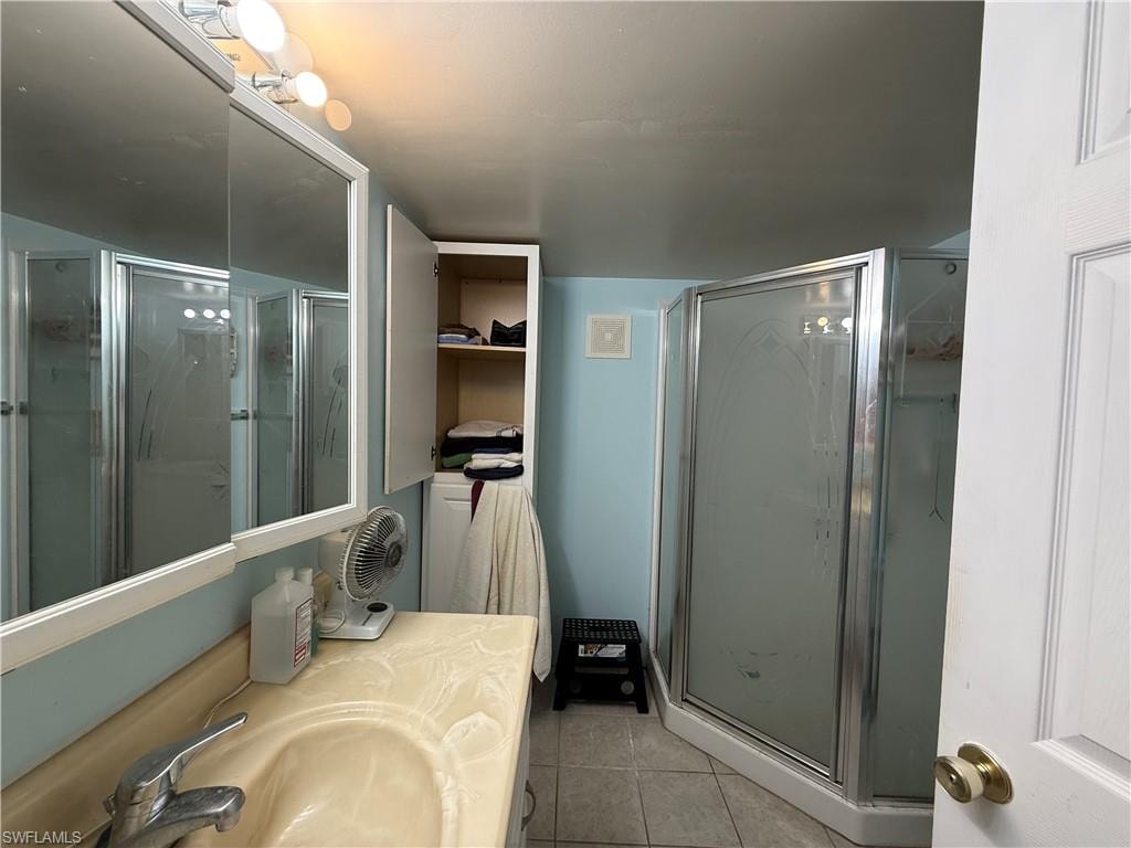 Bathroom featuring vanity, a stall shower, and light tile patterned flooring
