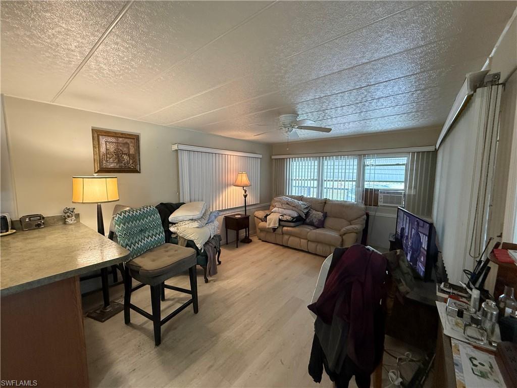 Living room featuring a textured ceiling, light wood-style flooring, and a ceiling fan