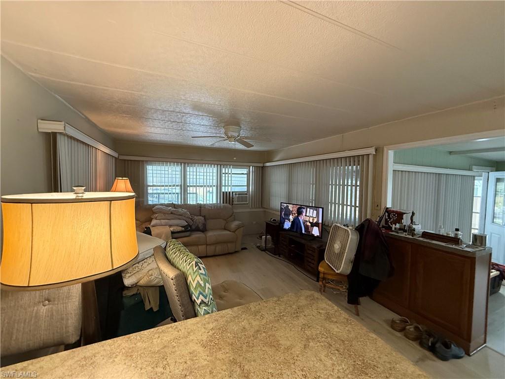 Living area with a ceiling fan, plenty of natural light, and wood finished floors
