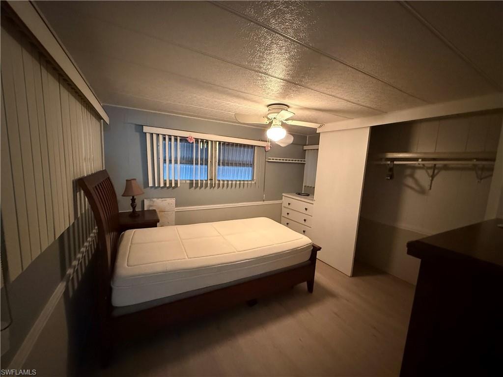 Bedroom with ceiling fan, a closet, a textured ceiling, and wood finished floors