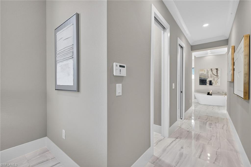 Corridor with light marble finish floors, ornamental molding, and recessed lighting