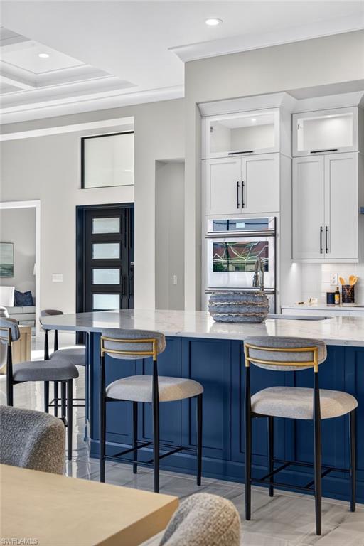 Kitchen with a kitchen breakfast bar, blue cabinetry, recessed lighting, backsplash, and crown molding