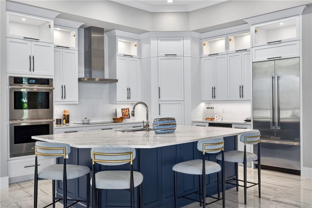 Kitchen featuring glass insert cabinets, appliances with stainless steel finishes, white cabinets, light stone countertops, and recessed lighting