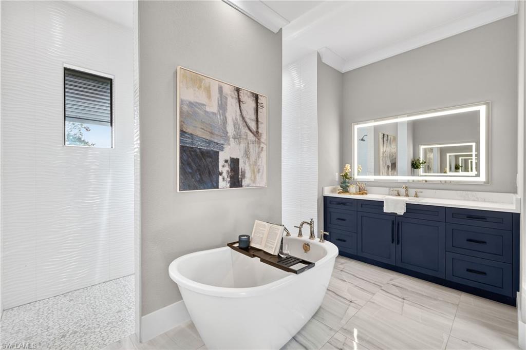 Full bathroom with vanity, a freestanding tub, ornamental molding, and walk in shower