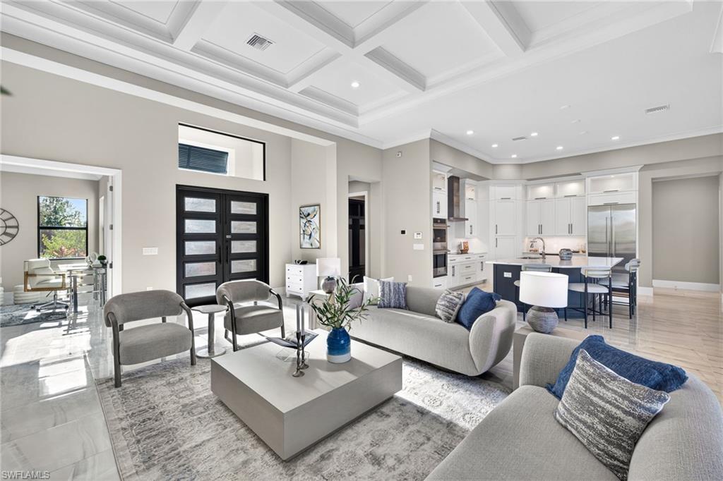Living area with coffered ceiling, crown molding, beamed ceiling, recessed lighting, and a high ceiling