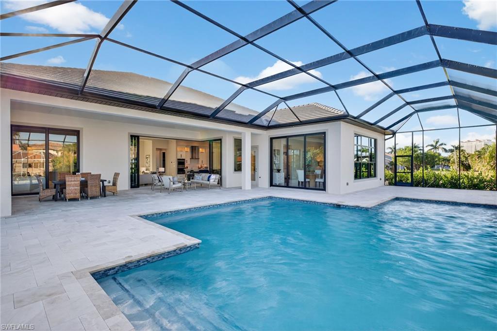 Rear view of house with a sunroom, an outdoor pool, glass enclosure, stucco siding, and a patio area