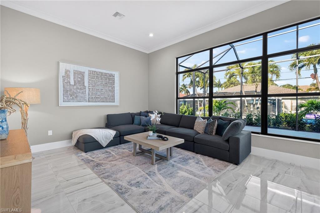 Living area with crown molding, light marble finish flooring, and recessed lighting