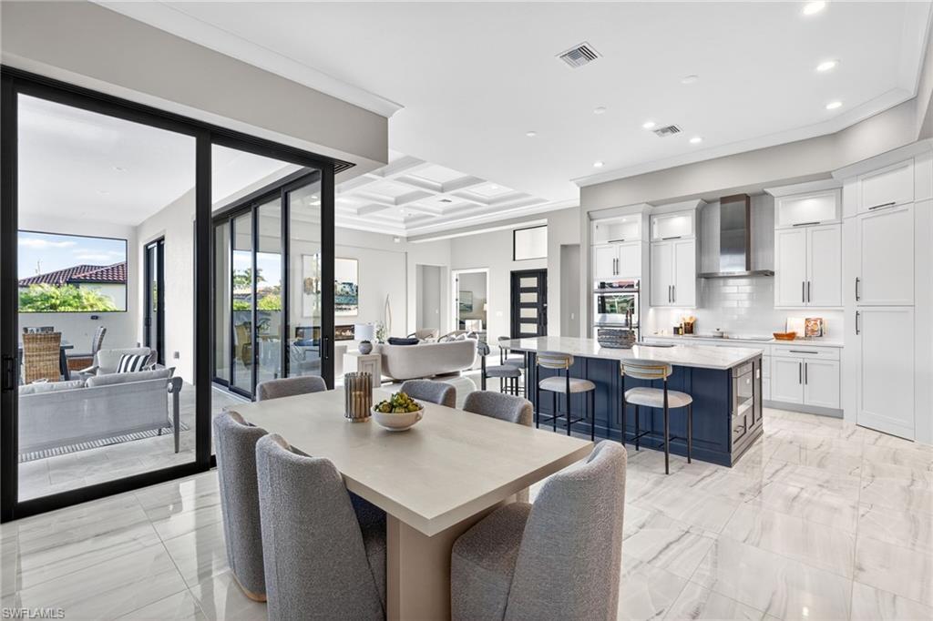 Dining area with coffered ceiling, light marble finish flooring, ornamental molding, beamed ceiling, and recessed lighting