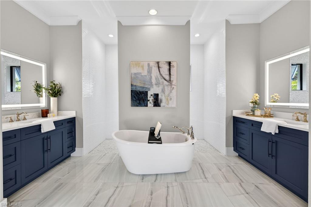 Bathroom featuring a freestanding tub, crown molding, two vanities, and recessed lighting