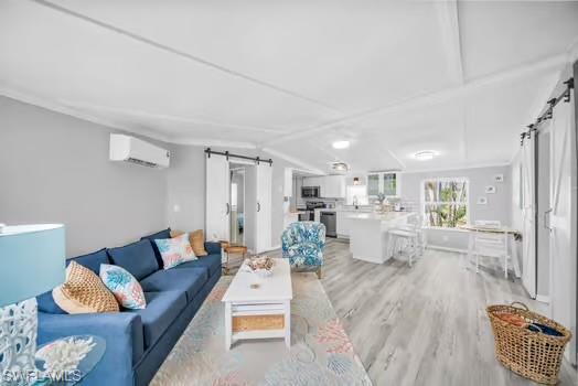 Living area with a barn door, light wood-type flooring, lofted ceiling, and a wall unit AC