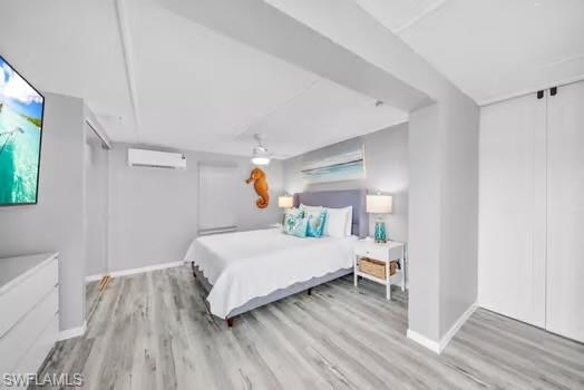 Bedroom featuring light wood-style flooring, ceiling fan, and an AC wall unit