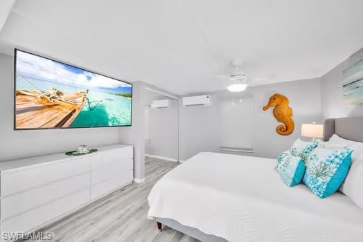 Bedroom with light wood-style floors, ceiling fan, and an AC wall unit
