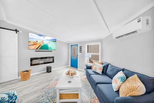 Living area featuring an AC wall unit, a barn door, and wood finished floors
