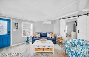 Living room with a barn door, wood finished floors, and healthy amount of natural light