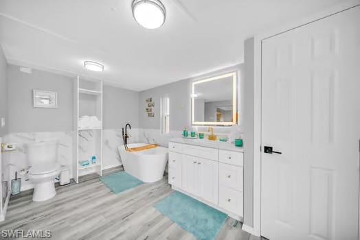 Full bathroom with vanity, a freestanding bath, and light wood-style floors