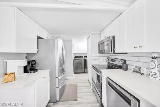 Kitchen with stainless steel appliances, washer and dryer, and white cabinetry