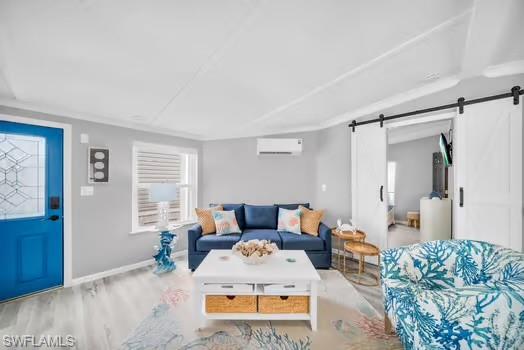 Living area with wood finished floors, a barn door, and an AC wall unit