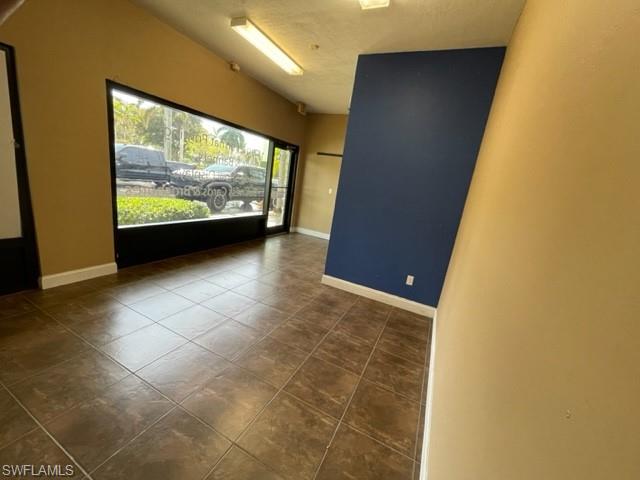 Spare room with baseboards and dark tile patterned flooring