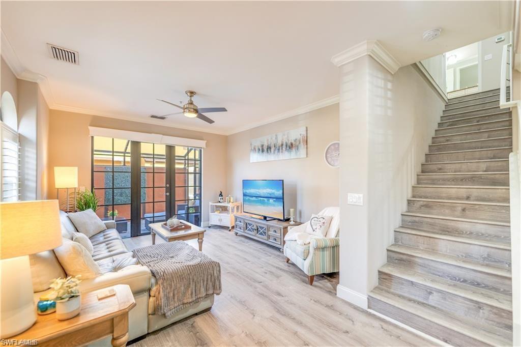Living area featuring ornamental molding, wood finished floors, stairs, ceiling fan, and french doors