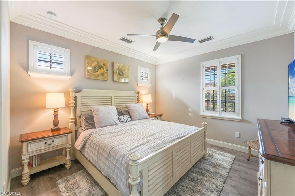 Bedroom with ornamental molding, wood finished floors, and ceiling fan