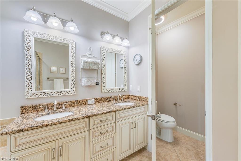 Bathroom with crown molding, double vanity, light tile patterned flooring, and a shower