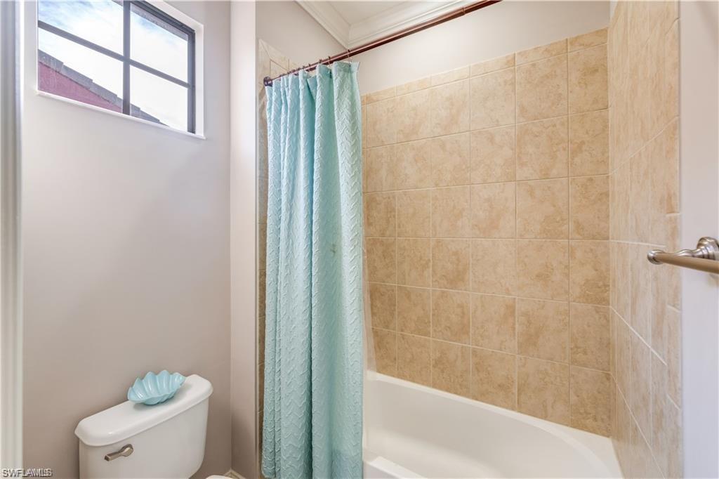 Bathroom featuring shower / tub combo and ornamental molding