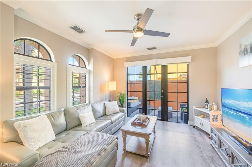 Living area featuring french doors, wood finished floors, crown molding, and a ceiling fan