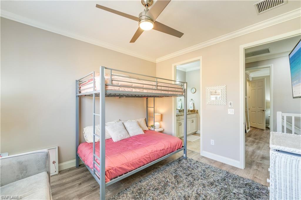 Bedroom with crown molding, light wood-type flooring, ensuite bath, and ceiling fan