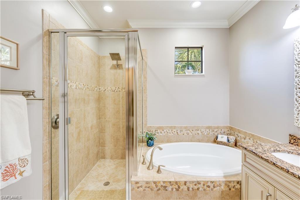 Bathroom featuring vanity, a bath, a shower stall, ornamental molding, and recessed lighting
