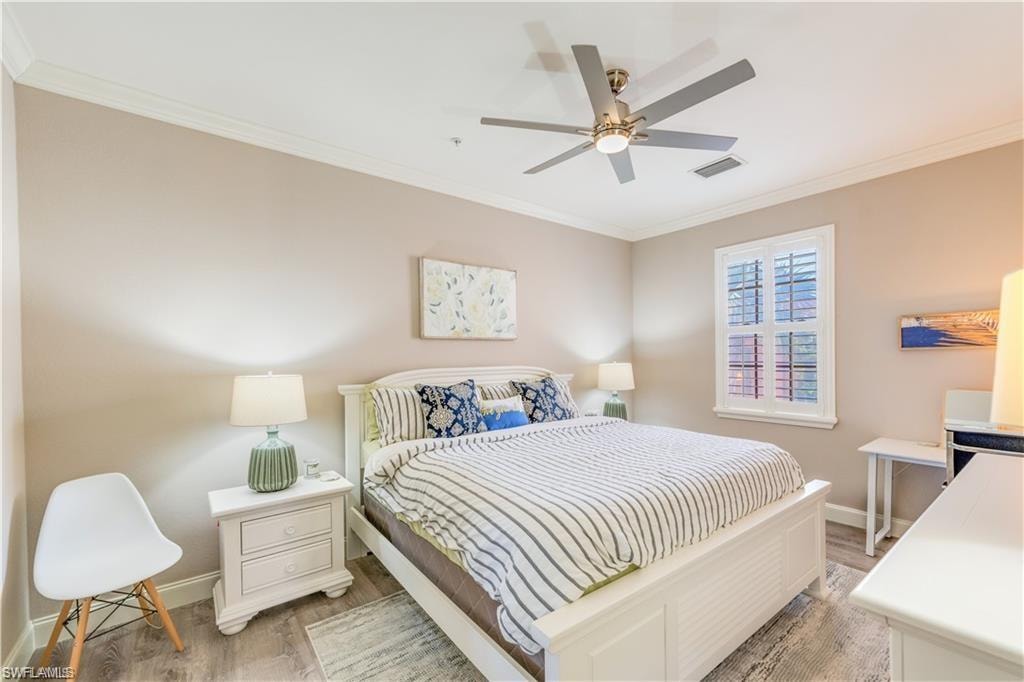 Bedroom with ornamental molding, light wood finished floors, and a ceiling fan