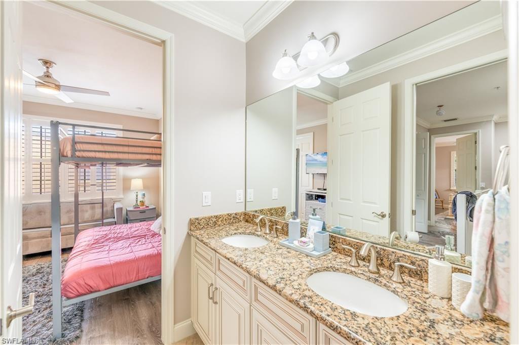 Ensuite bathroom featuring ornamental molding, light wood-style flooring, double vanity, and a ceiling fan