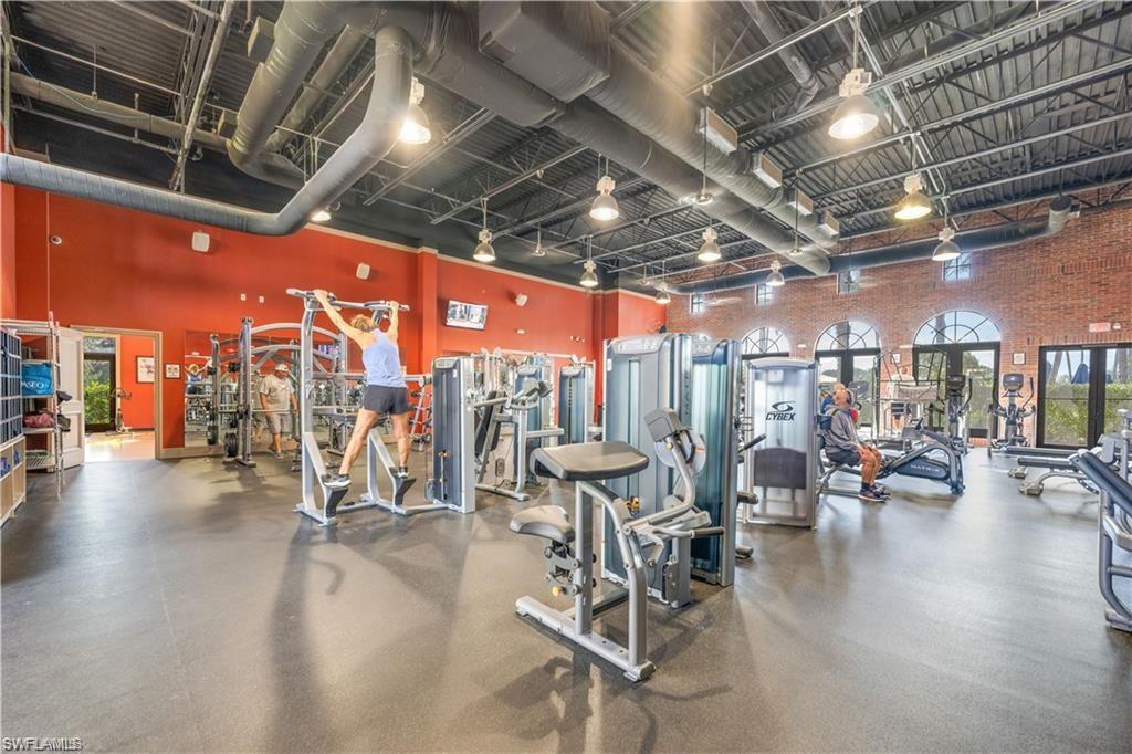 Exercise room featuring a towering ceiling and brick wall