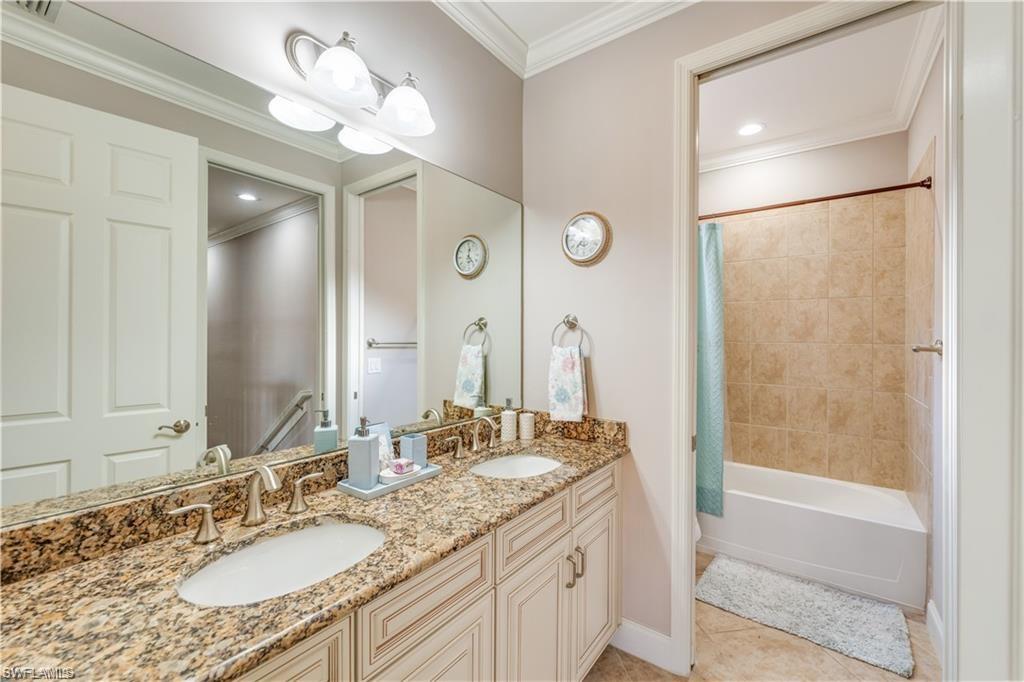 Full bath featuring ornamental molding, shower / bath combo, double vanity, and light tile patterned flooring