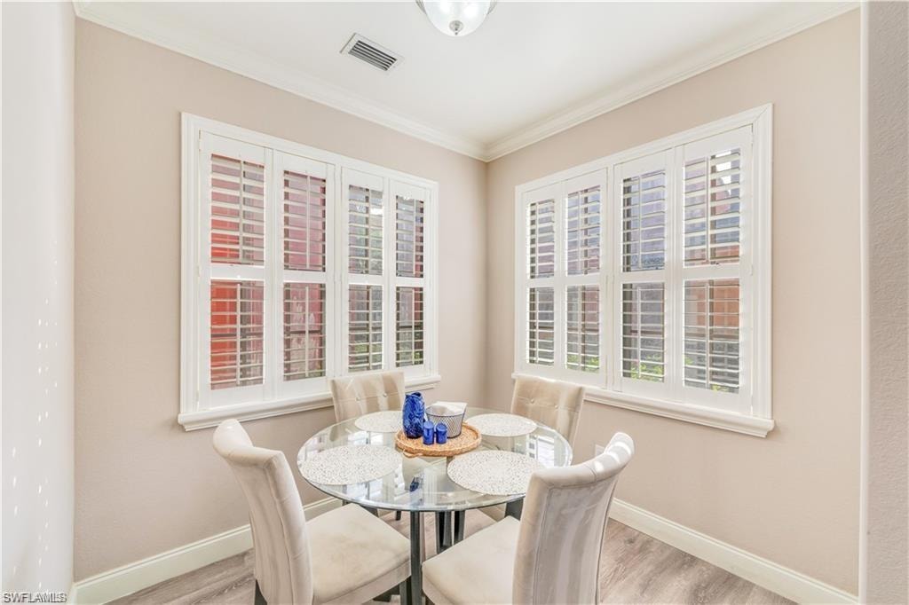Dining area with light wood-type flooring and crown molding
