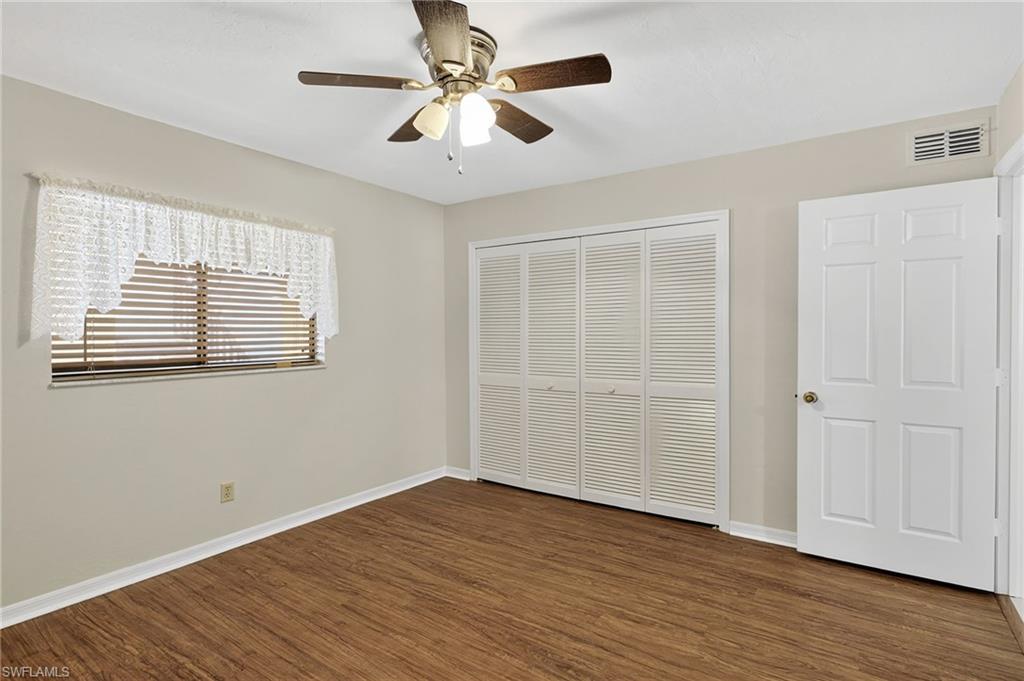 Unfurnished bedroom with dark wood-style floors, a closet, and a ceiling fan