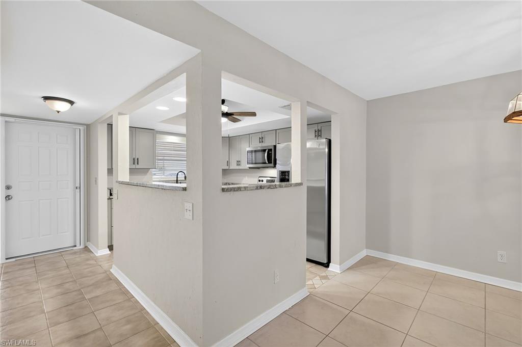 Kitchen with stainless steel appliances, light tile patterned floors, a ceiling fan, and light stone countertops