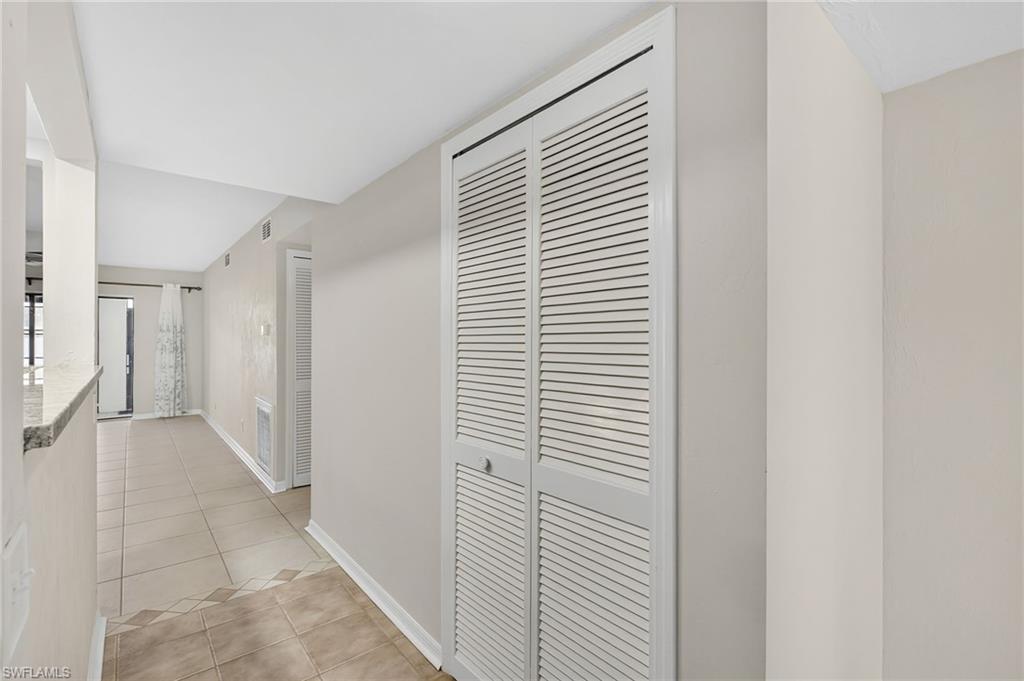 Hallway featuring light tile patterned flooring and baseboards
