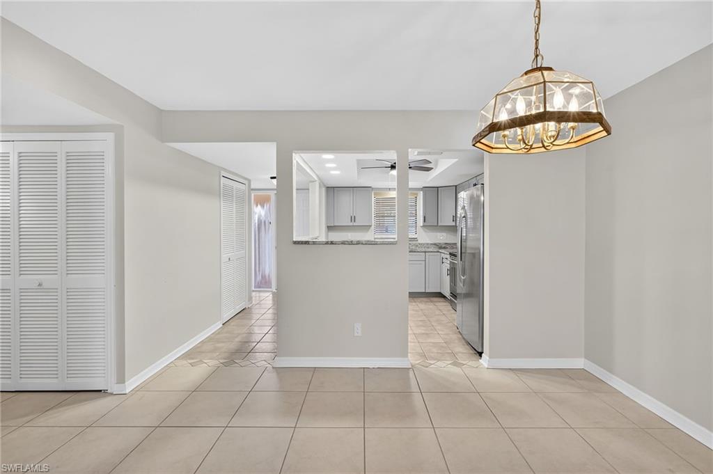 Kitchen with gray cabinetry, light tile patterned floors, a chandelier, hanging light fixtures, and freestanding refrigerator