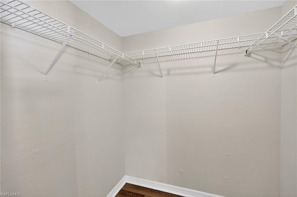Walk in closet with dark wood-type flooring