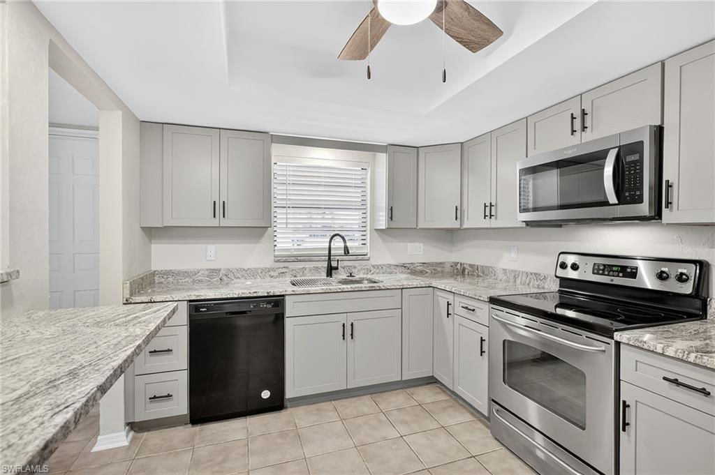 Kitchen featuring stainless steel appliances, a tray ceiling, a ceiling fan, and gray cabinetry