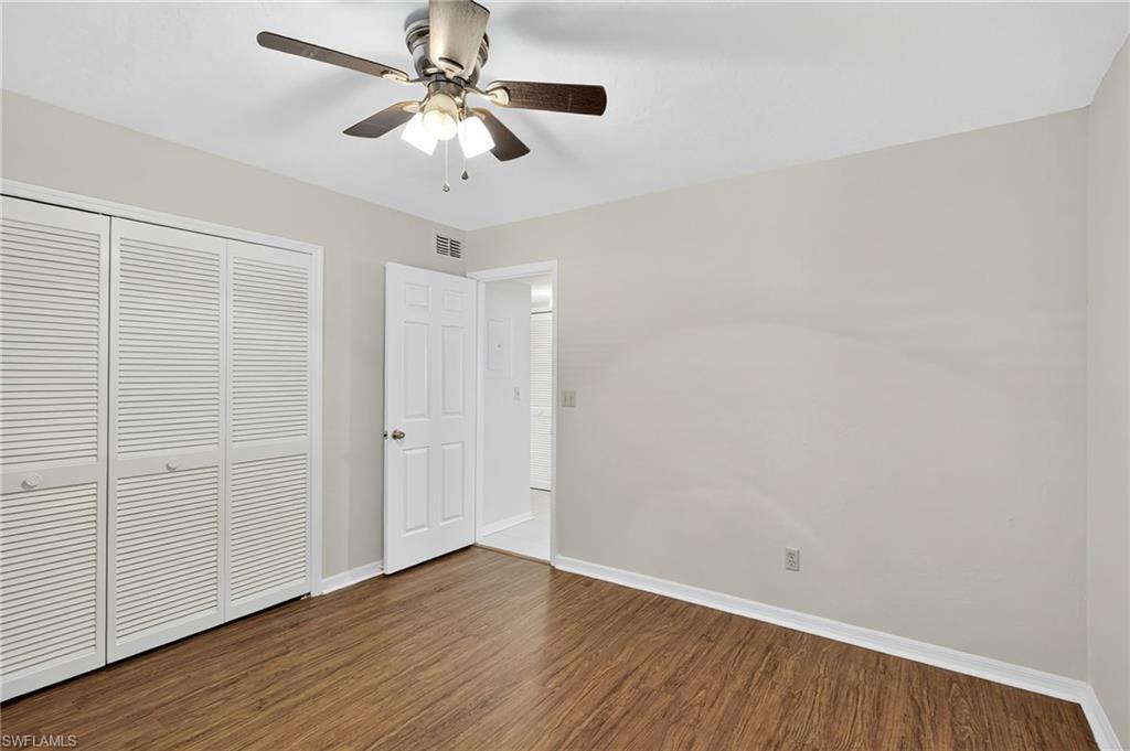 Unfurnished bedroom with dark wood-style floors, a closet, and a ceiling fan