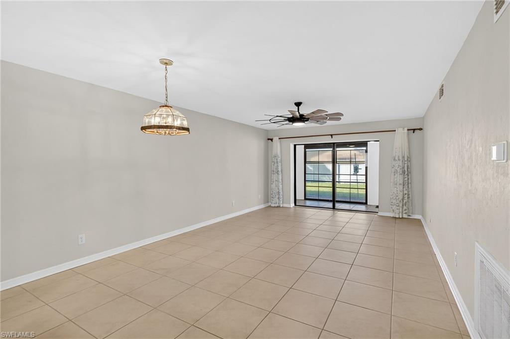 Empty room featuring light tile patterned floors, a ceiling fan, and a chandelier